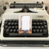 Beige adressticker met okergele typemachine en wit papier op typemachine