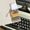 Detail van licht gelinieerd beige notitieblok met typemachine en veer met op achtergrond typemachine