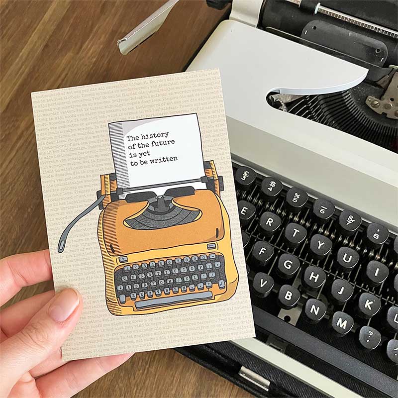 Beige postkaart met okergele typemachine en tekst 'the history of the future is yet to be written' op het papier